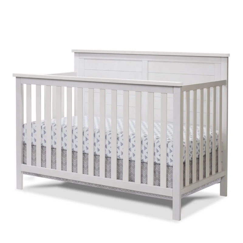 White crib with a mattress and gray bedding on a white background