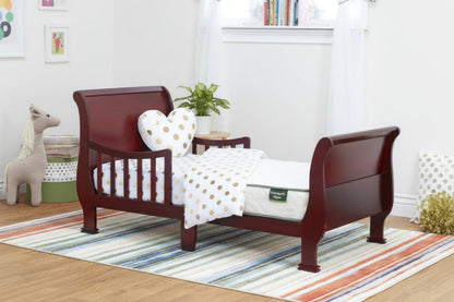 Children's wooden bed with white and gold polka dot bedding in a room with a striped rug and toys.