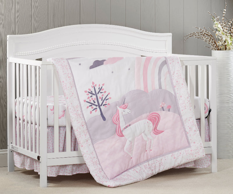 White crib with pink unicorn-themed bedding in a nursery setting