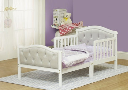 White toddler bed with tufted headboard in a room with purple walls and a window.