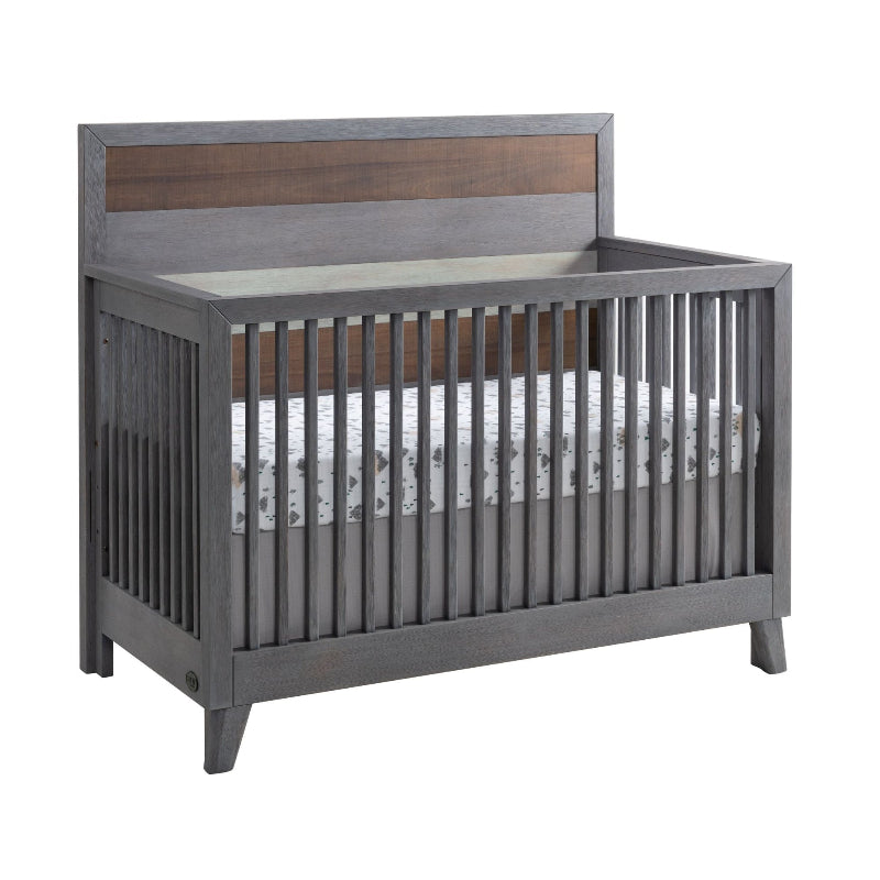 A 3-in-1 baby crib with a gray wood finish and a brown wood accent panel on the headboard, shown with a patterned mattress on a white background.