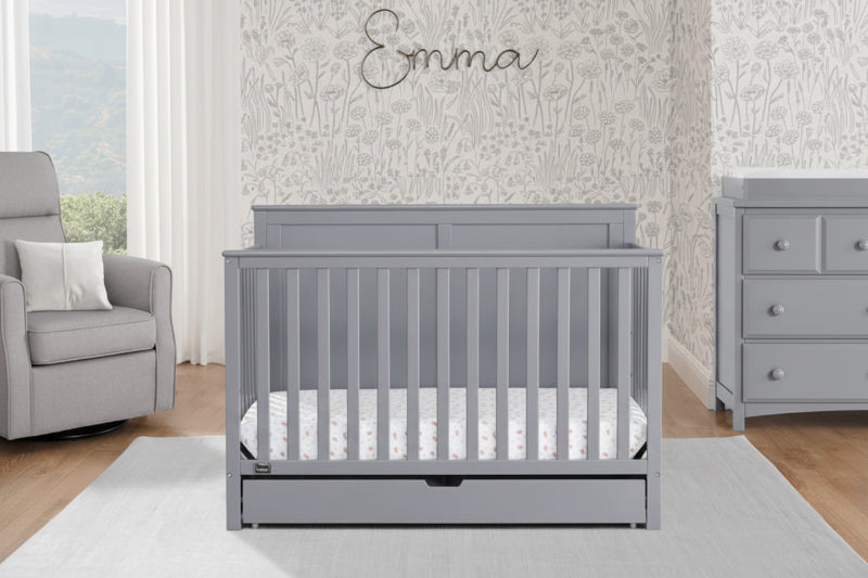 Gray crib in a nursery with matching dresser and decorative elements.