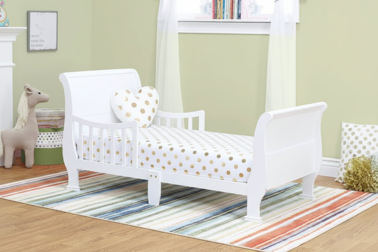 Children's wooden bed with white and gold polka dot bedding in a room with a striped rug and toys.