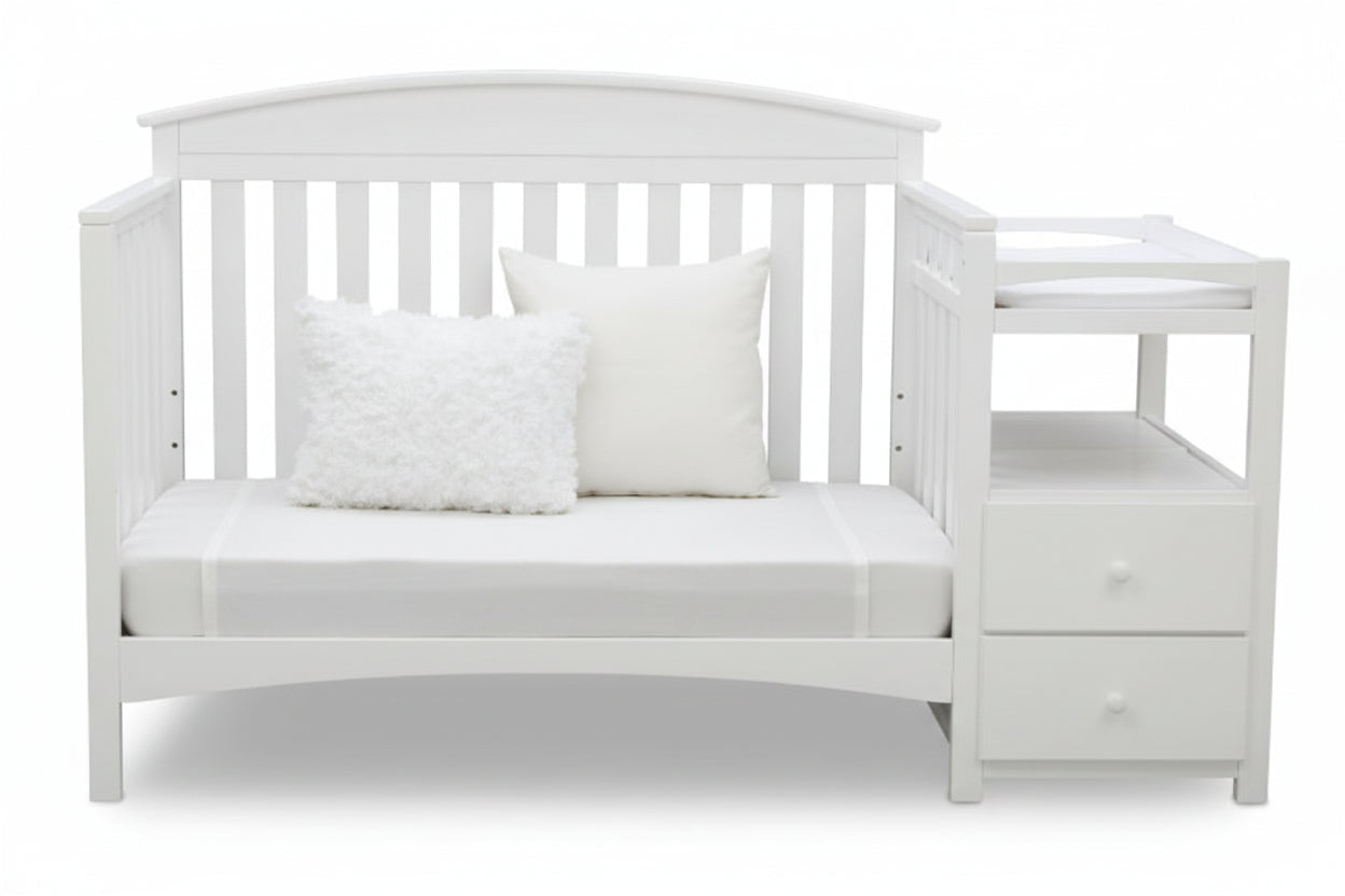 Gray crib with white bedding and pillows on a white background