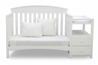 Gray crib with white bedding and pillows on a white background