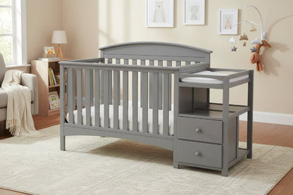 Gray crib with changing table in a nursery setting