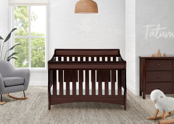 Nursery room with a wooden crib, gray chair, and dresser.