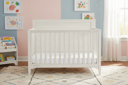 White crib with white bedding on a white background