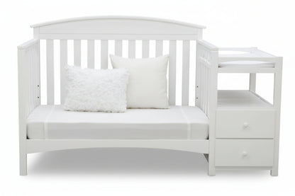 Gray crib with white bedding and pillows on a white background