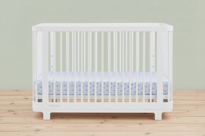 White crib with a blue and white crib sheet on a white background