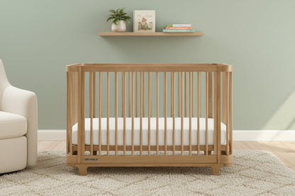 Wooden crib with a white mattress on a plain background