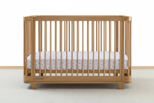 Wooden crib with a white mattress on a plain background