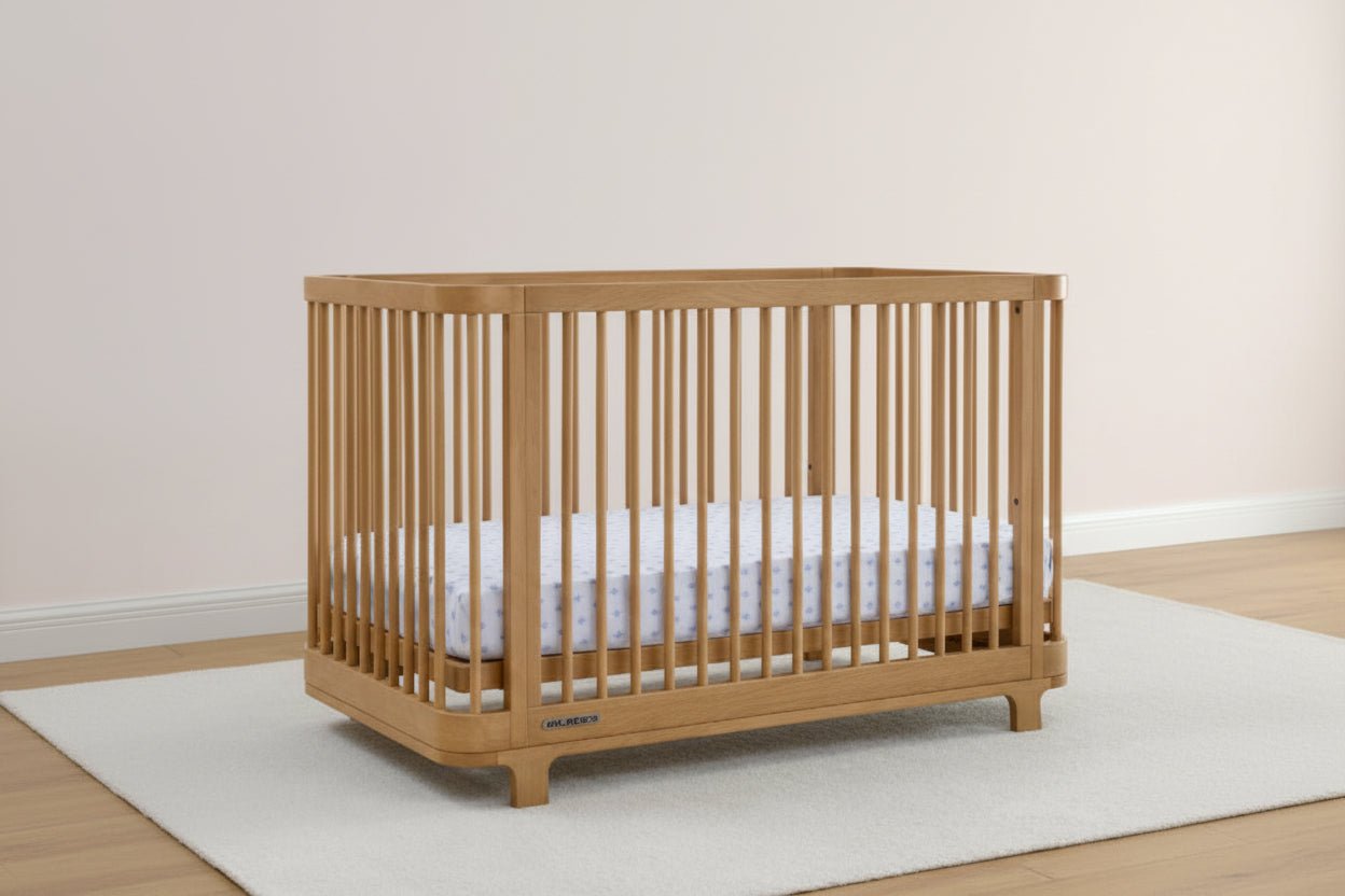 Wooden crib with white mattress on a light wooden floor and white wall background