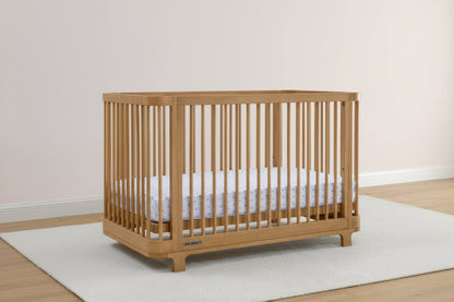 Wooden crib with white mattress on a light wooden floor and white wall background