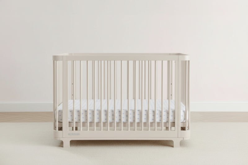Beige crib with white mattress on a light gray background