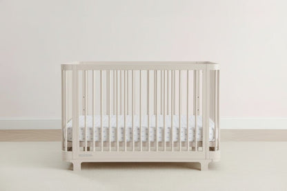 Beige crib with white mattress on a light gray background
