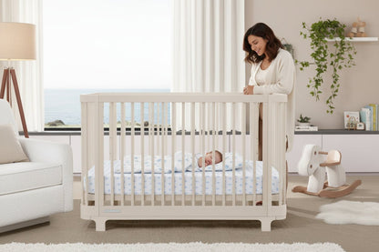 White crib in a room with light-colored walls and furniture.