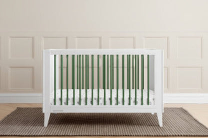 White crib in a room with green paneling