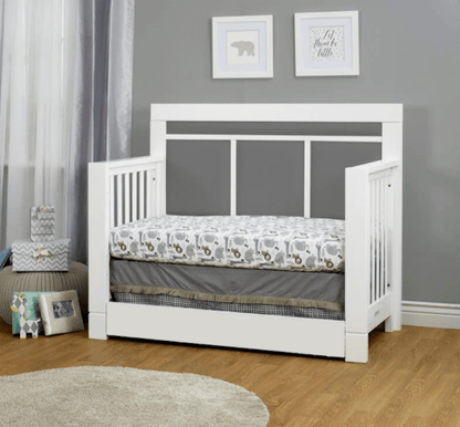 White crib with bedding in a room with gray walls and decorative elements.