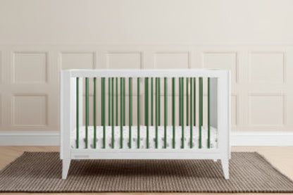White crib in a room with green paneling